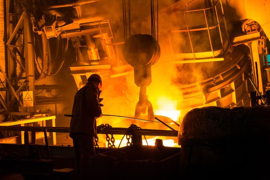 Realistic industrial scene in a Tier-1 automotive supplier facility: clean, well-lit foundry floor with induction furnace melting aluminum for engine blocks, visible operator monitoring digital controls, minimal dross, and no open flames or electrodes
